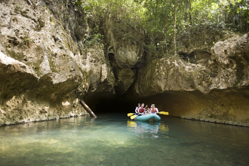 A group of adventure tourists traversing four caves by raft and kayak on Caves Branch River in Central Belize.
