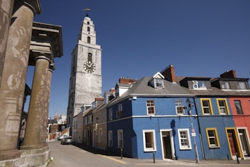 Shandon tower above a row of painted houses and columns of the butter museum.