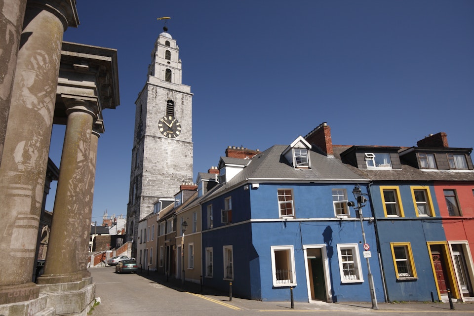 Shandon tower above a row of painted houses and columns of the butter museum.