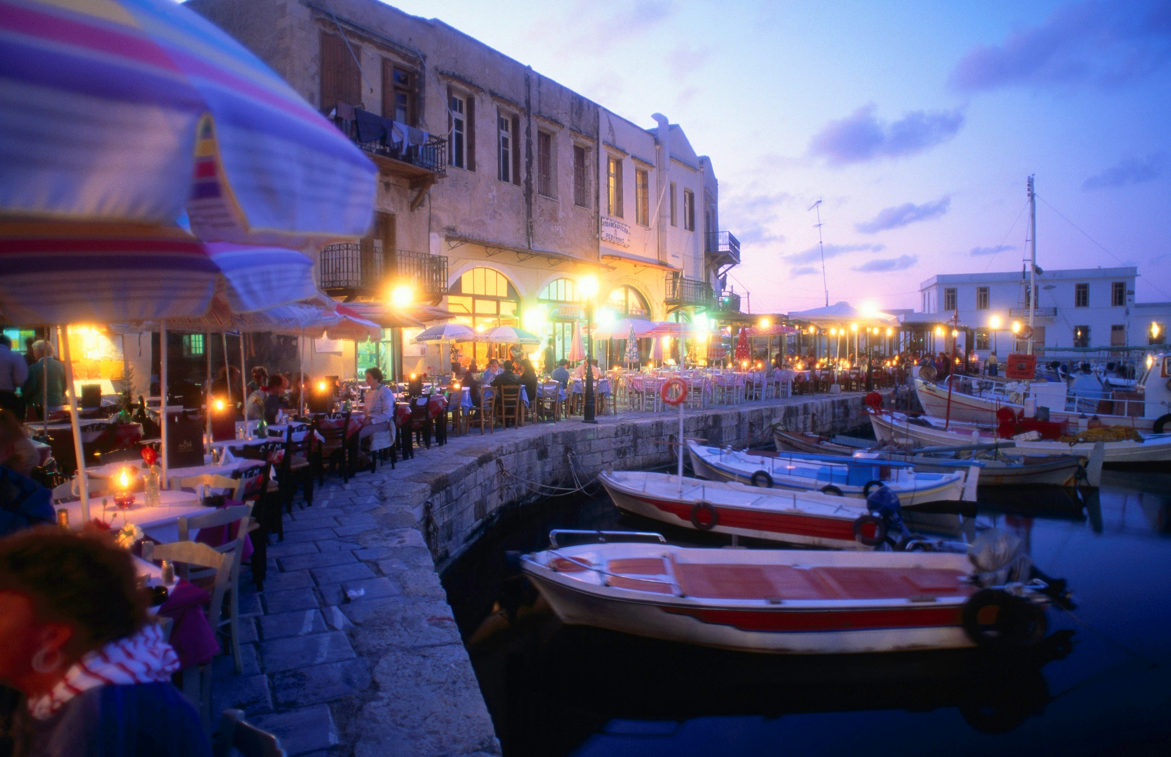 Night-life: Fishing boats moored in the harbour, while people eat out along the waterfront - Rethymno, Rethymno Province, Crete