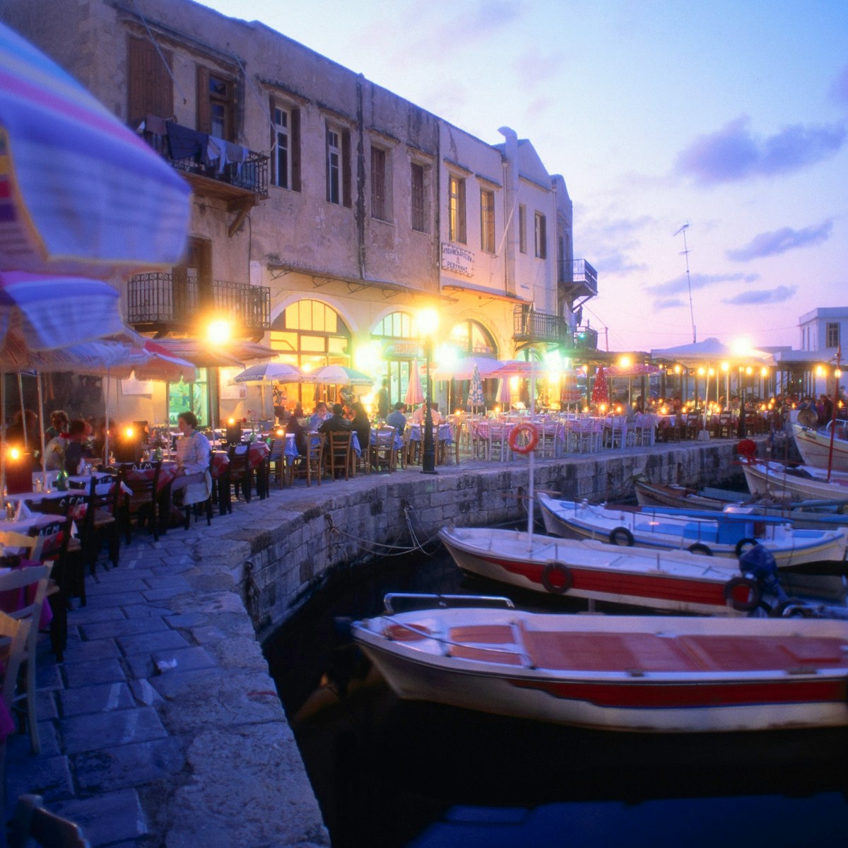 Night-life: Fishing boats moored in the harbour, while people eat out along the waterfront - Rethymno, Rethymno Province, Crete