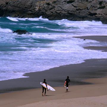 Surfers heading out to the breaks off Praia do Guincho.