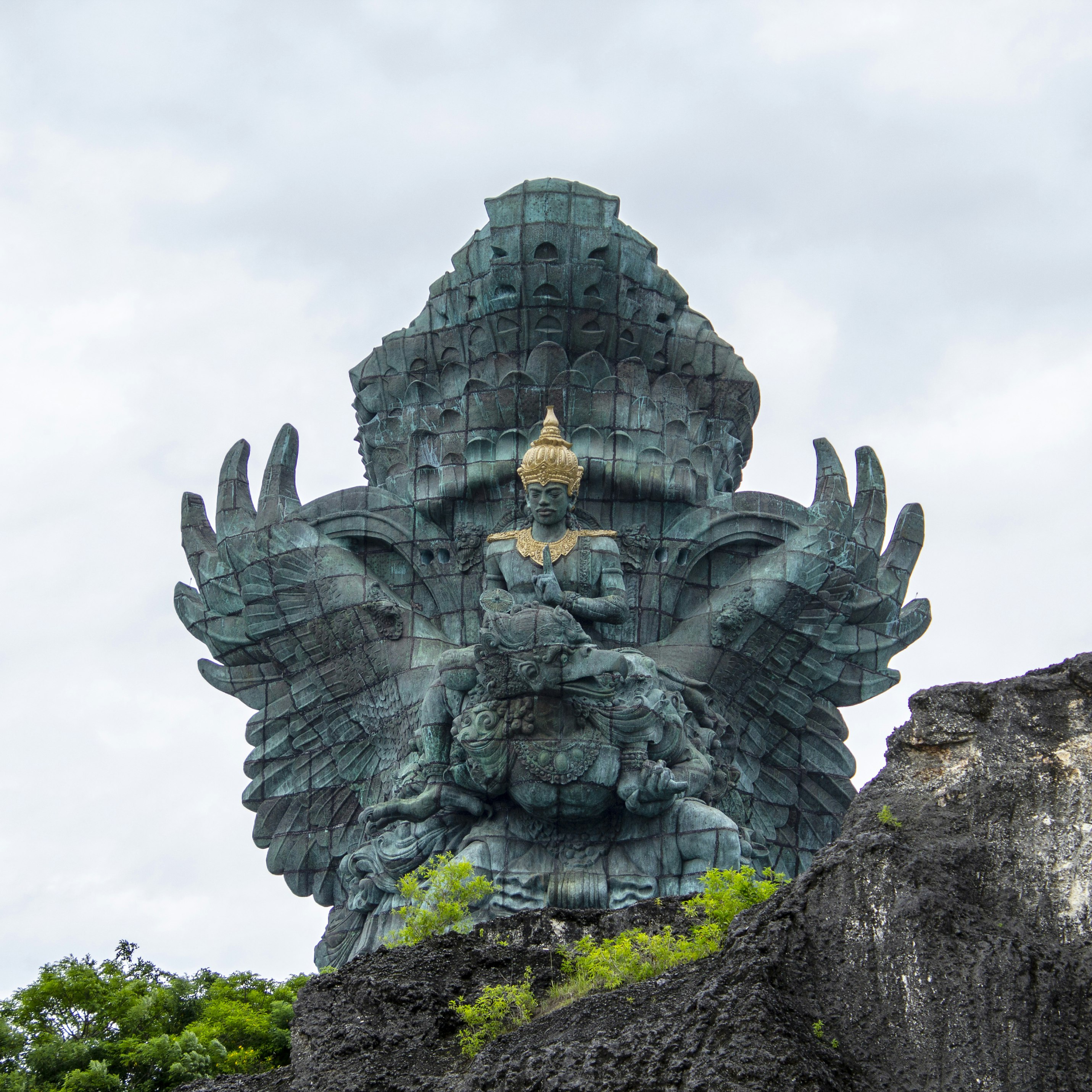 Bali, Indonesia - January 2019 - Garuda Wisnu Kencana statue towers above the rocky cliffs. Located in Garuda Wisnu Kencana Cultural Park it was designed by Nyoman Nuarta and inaugurated in September 2018, 28 years since its inception. Made of brass and copper sheeting and a wingspan of 64m ,the total height of the monument is 121 m (397ft), making it Indonesia's tallest and one of the world's largest.