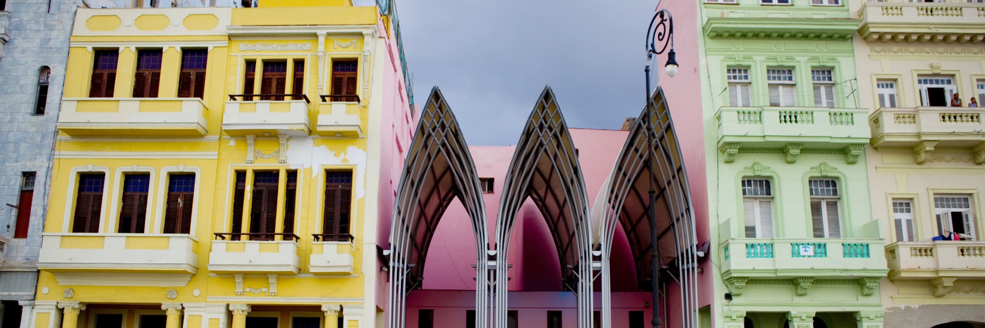 Vintage car passing modern bar nestled between dilapidated Art Nouveau buildings along the Av de Malecon.