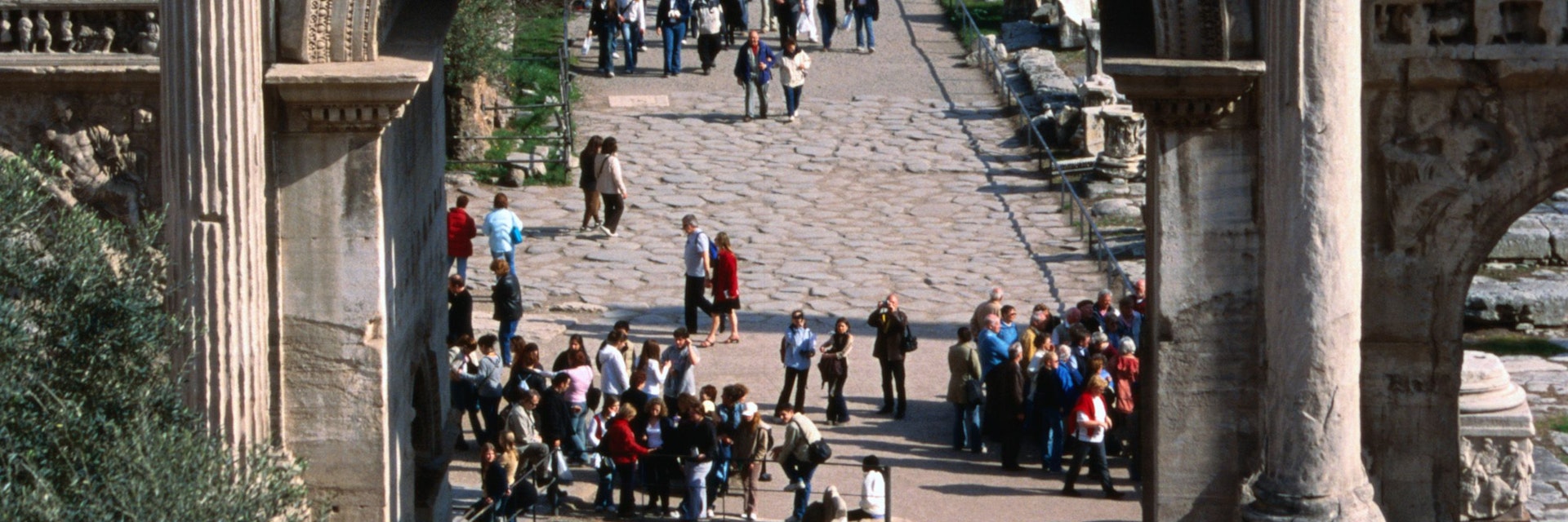 Crowds of tourists on a cobbled path behind Arco di Settimio Severo, Roman Forum.
