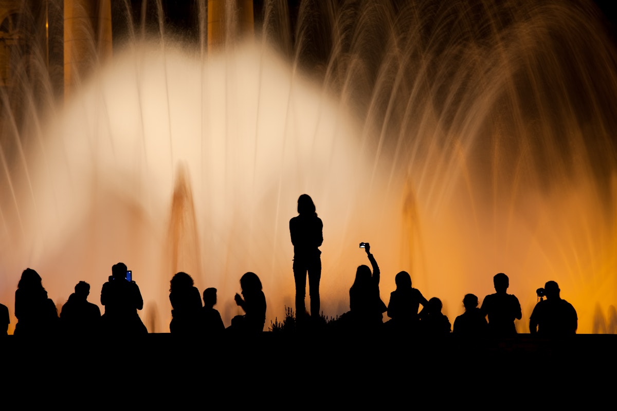 People silhouette against Magic Fountain illuminated at night in Barcelona, Catalonia, Spain.