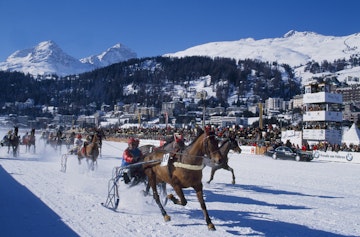 Switzerland, St Moritz, White Turf race meeting. A trotting race with jockeys driving horse-drawn sleighs on the frozen lake at St Moritz