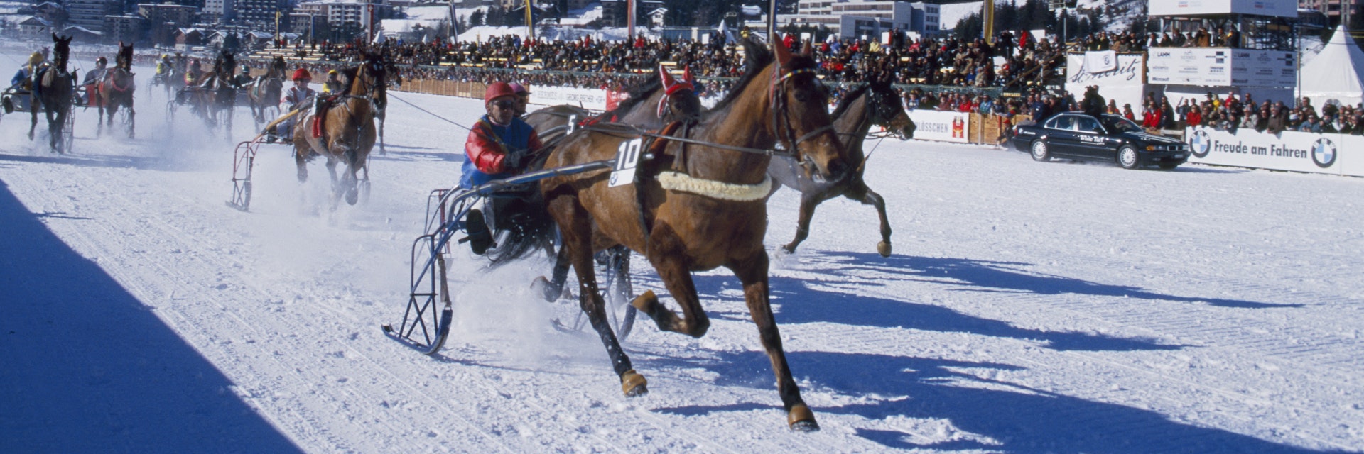 Switzerland, St Moritz, White Turf race meeting. A trotting race with jockeys driving horse-drawn sleighs on the frozen lake at St Moritz