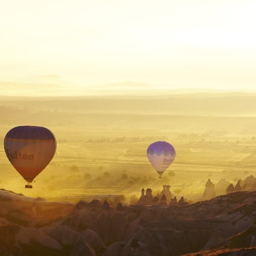Balloons at dawn over fairy chimney rock formations.