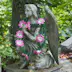 Artifical flowers decorating small winged angel statue on grave at Lychakivske Cemetery.