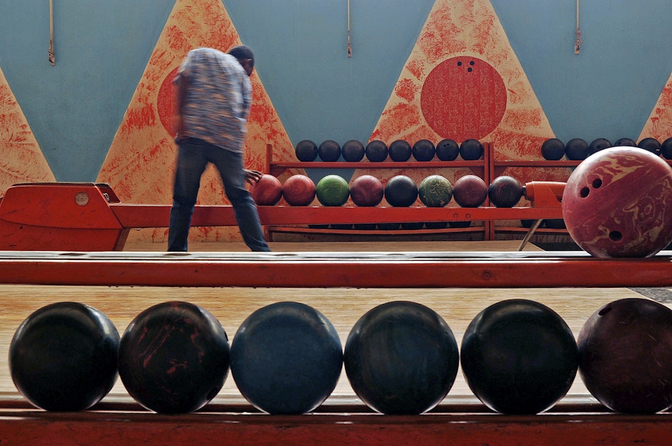 TO GO WITH AFP STORY BY JENNY VAUGHAN.A man picks up a bowling ball in the Asmara bowling alley in Asmara, the capital of Eritrea, on July 20, 2013. Eritrea's capital Asmara boasts buildings unlike anywhere else in Africa, a legacy of its Italian colonial past, when architects were given free reign for structures judged too avant garde back home. Yet while many of the buildings survived unscathed from a decades long liberation war from Ethiopia that ravaged settlements elsewhere, today, preservation and restoration projects have been hampered, threatening to erode the country's rich cultural heritage. AFP PHOTOS / JENNY VAUGHAN        (Photo credit should read JENNY VAUGHAN/AFP/Getty Images)