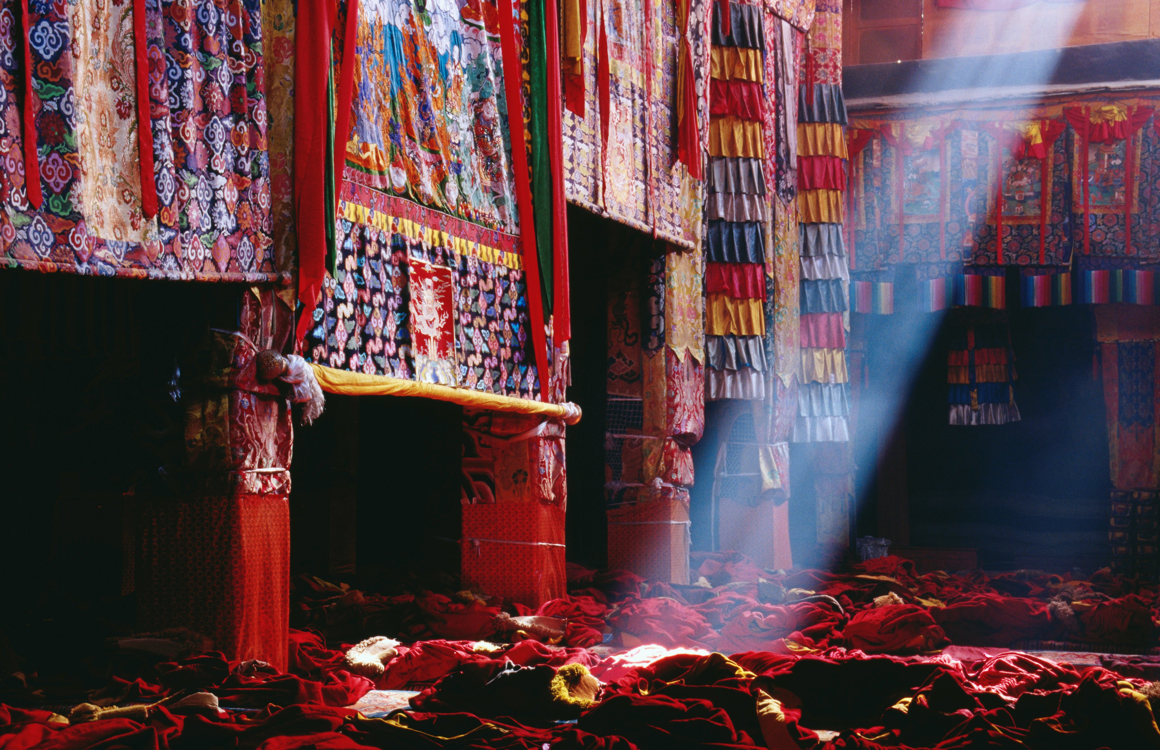 Thangkas highlighted by ray of light, Assembly Hall, Ganden Monastery.