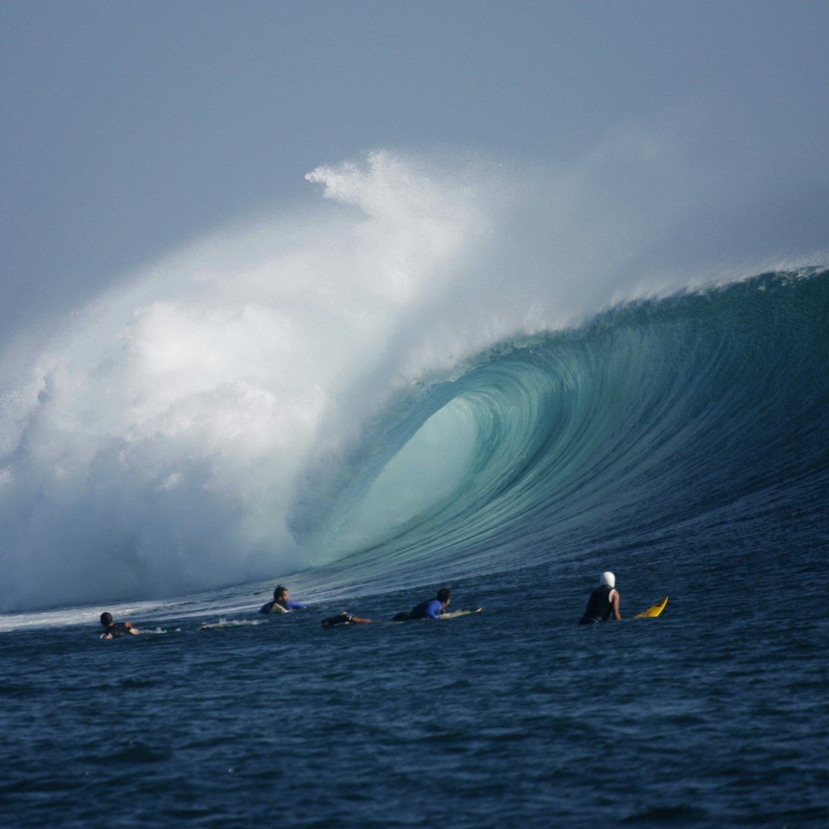 Surfers look on as a large wave rolls through at G-Land, Java, Indonesia.
