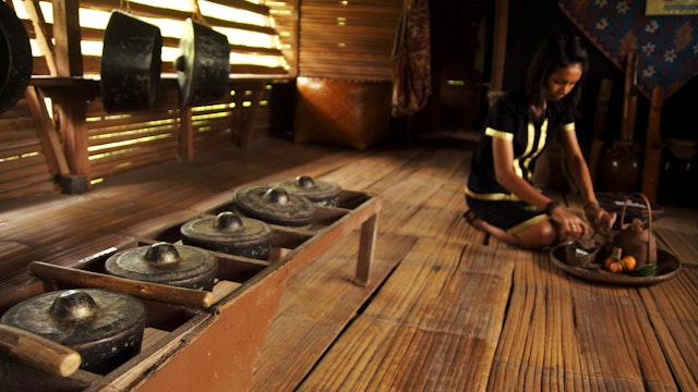 Monsopiad woman shows tourists around traditional house at Kadazan-Dusun Monsopiad Cultural Village.