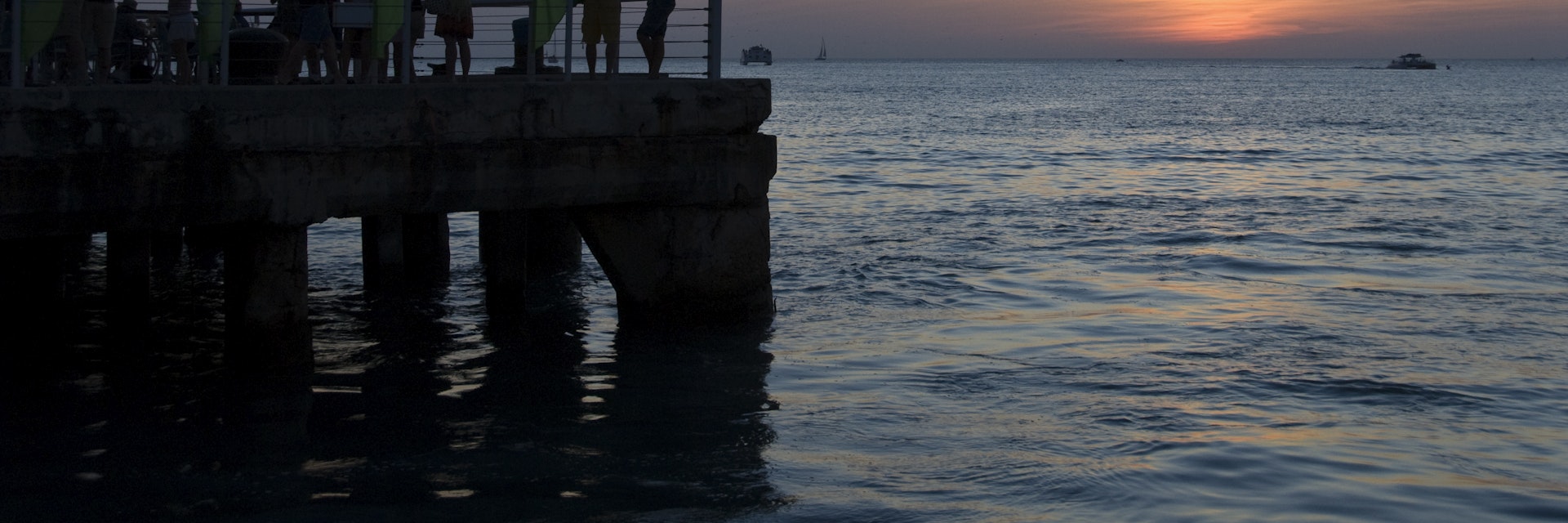 Tourists and locals enjoy cocktails while viewing the sunset from pier at Mallory Square.