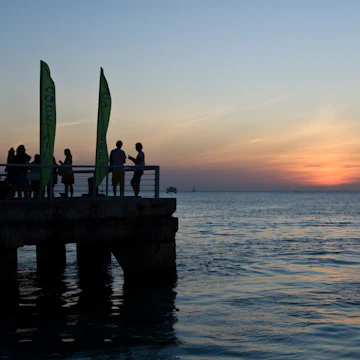 Tourists and locals enjoy cocktails while viewing the sunset from pier at Mallory Square.
