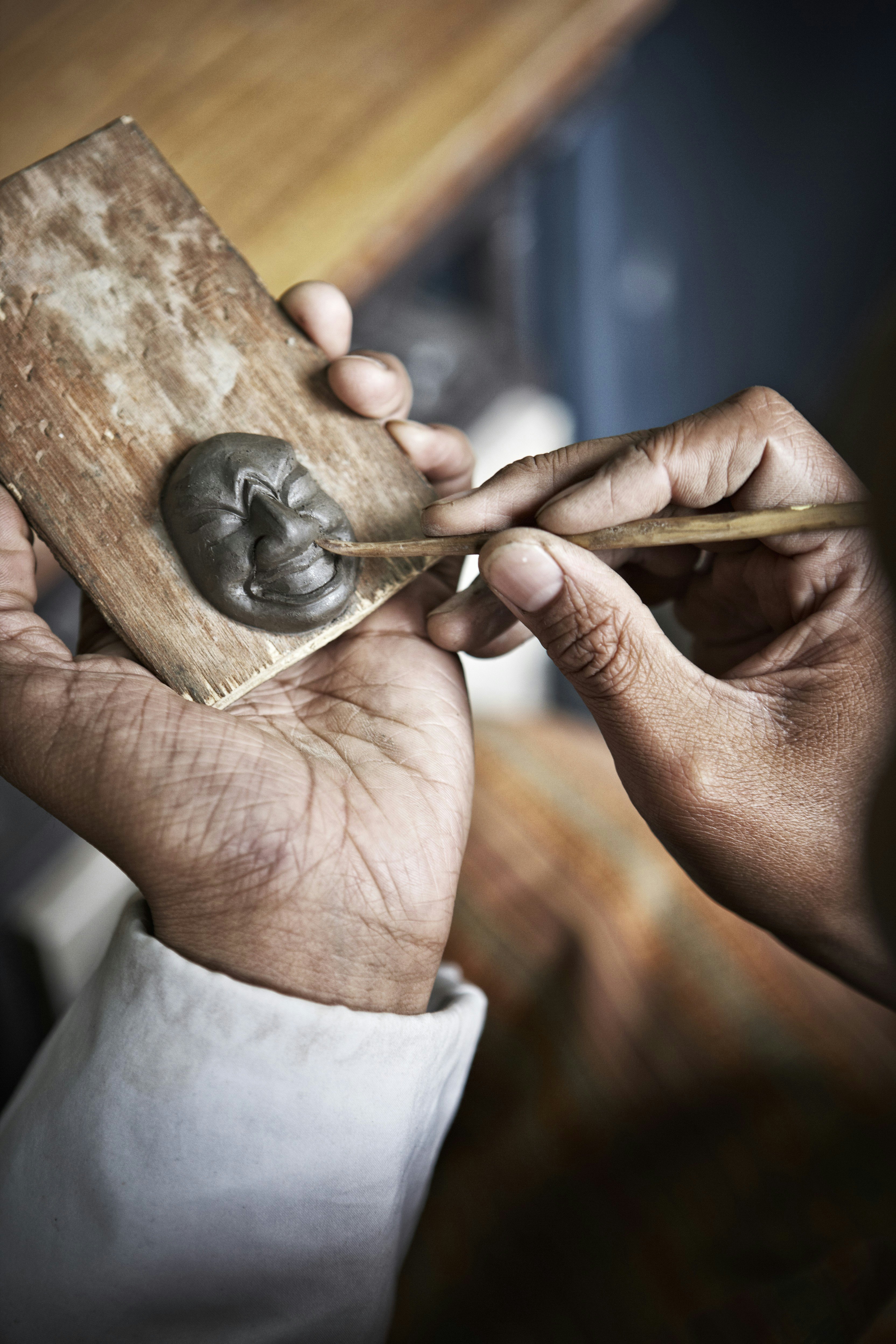 Man moulding miniature clay mask at National Institute for Zorig Chusum.