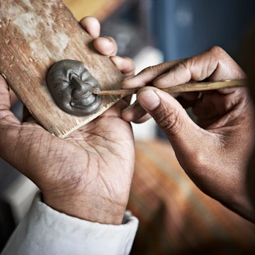 Man moulding miniature clay mask at National Institute for Zorig Chusum.