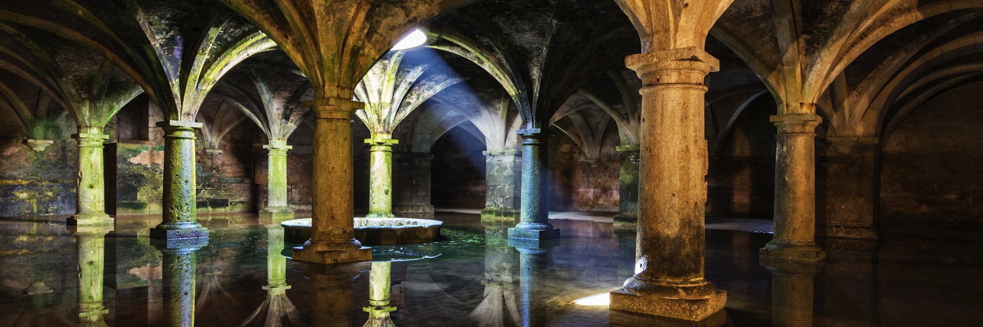Ornate tile arches illuminated near skylight reflecting in water