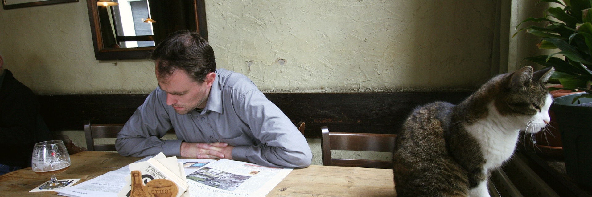 Man reading near cat on table at Jenever cafe De Vagant on Reyndersstraat.