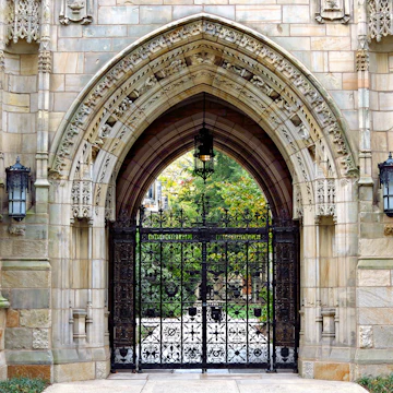 This decorative iron gate is the entrance to the Memorial Quadrangle on the campus of Yale University. The gate beneath Harkness Tower, crafted by Samuel Yellin, is the most ornate of his many works at Yale.