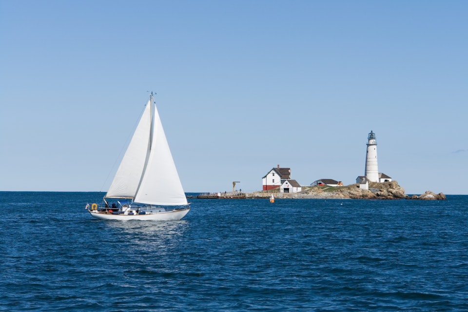 A sailboat crosses in front of Boston Light; Shutterstock ID 9570529; Your name (First / Last): Trisha Ping; GL account no.: 65050; Netsuite department name: Online Editorial; Full Product or Project name including edition: Trisha Ping/65050/Online Editorial/New England