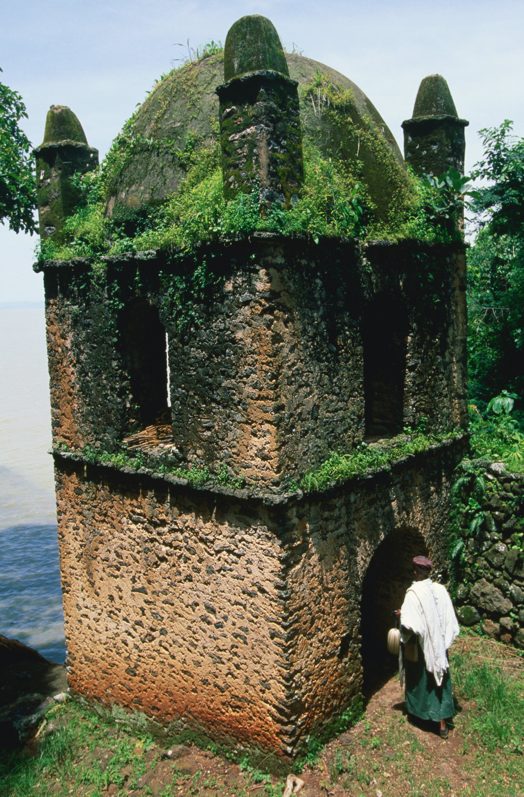 A man entering the grass and moss covered bastion of the island monastery, Narga Selassie, on Lake Tana