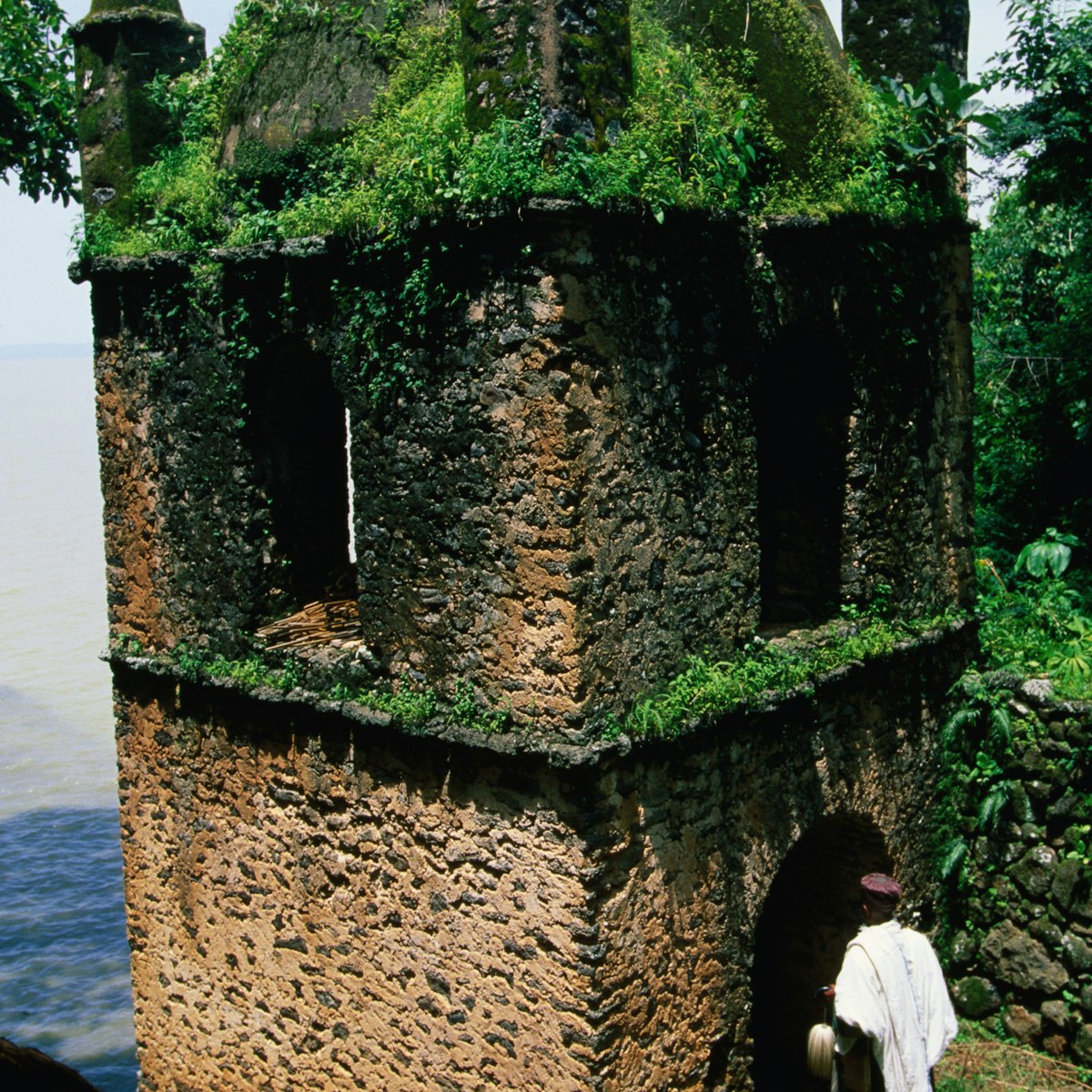 A man entering the grass and moss covered bastion of the island monastery, Narga Selassie, on Lake Tana