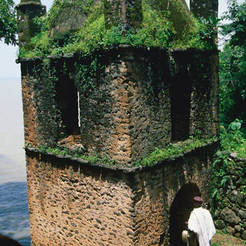 A man entering the grass and moss covered bastion of the island monastery, Narga Selassie, on Lake Tana