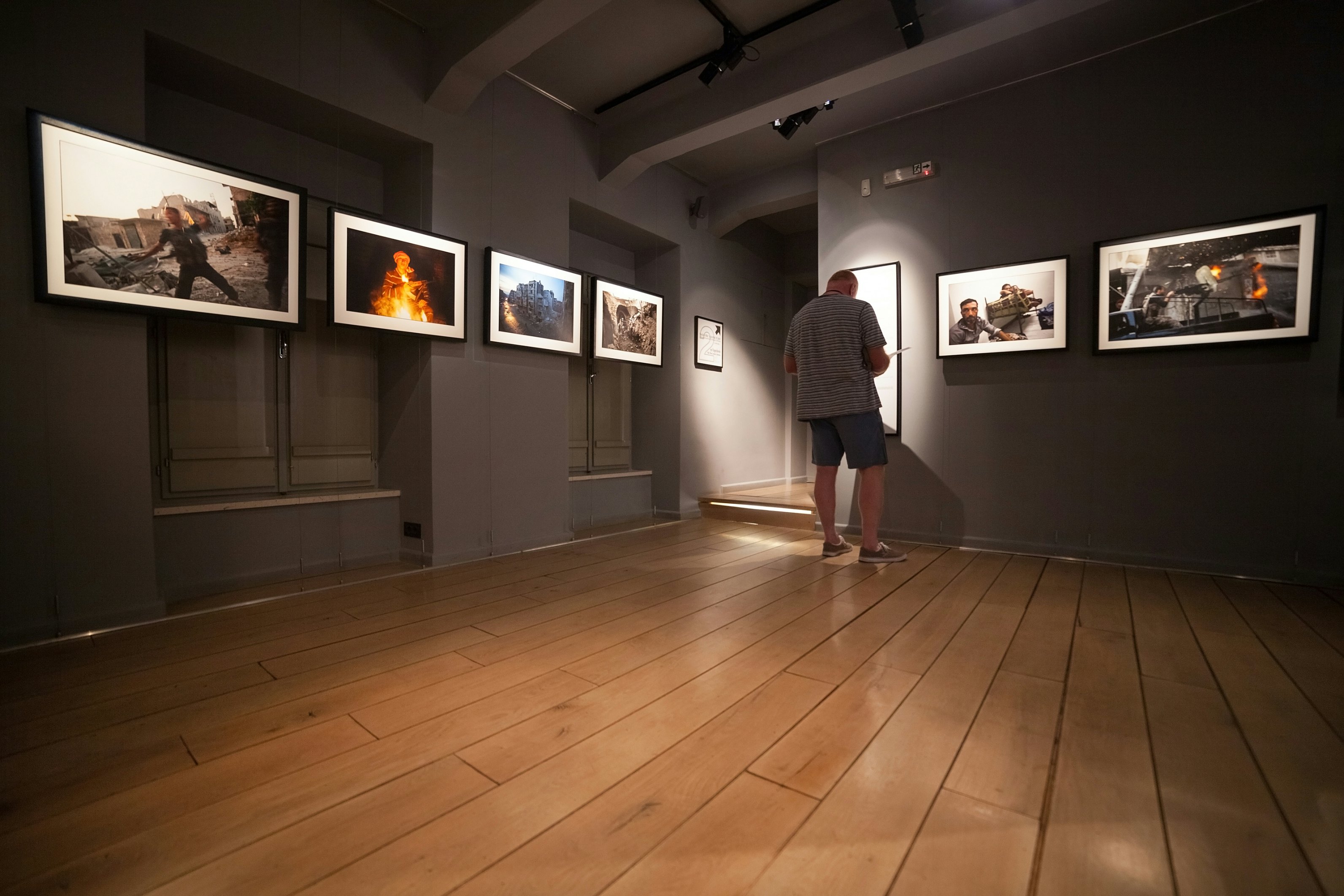 DUBROVNIK, CROATIA - MAY 26, 2014: Tourist looking at photos in the War photo limited gallery. There is 350m2 of exhibition space on two floors. ; Shutterstock ID 215780338; Your name (First / Last): Josh Vogel; GL account no.: 56530; Netsuite department name: Online Design; Full Product or Project name including edition: Digital Content/Sights