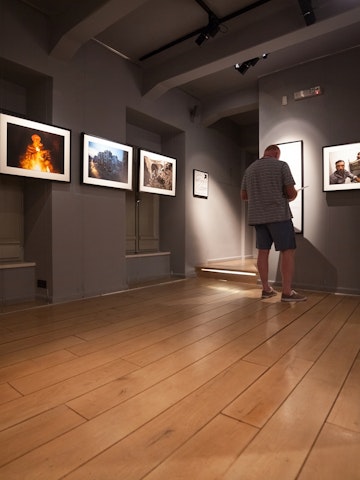DUBROVNIK, CROATIA - MAY 26, 2014: Tourist looking at photos in the War photo limited gallery. There is 350m2 of exhibition space on two floors. ; Shutterstock ID 215780338; Your name (First / Last): Josh Vogel; GL account no.: 56530; Netsuite department name: Online Design; Full Product or Project name including edition: Digital Content/Sights