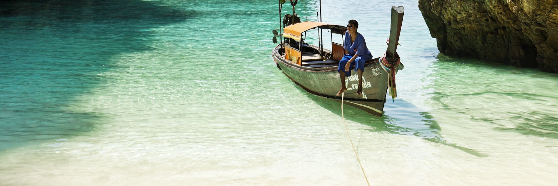 Boatman sitting on longtail boat in Loh Samah bay.