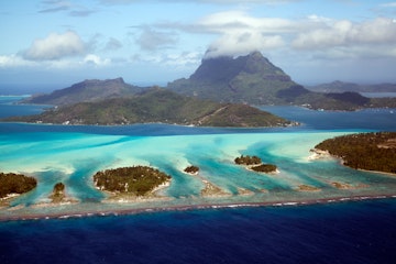 Aerial view of Bora Bora with Mount Otemanu, Mount Pahia , and the surrounding motus, taken from a helicopter in September 2012.