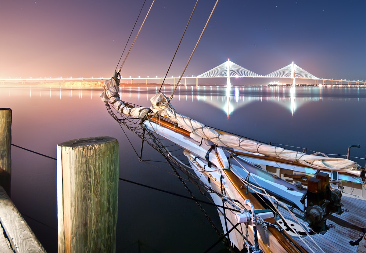 Nightfall over Charleston harbor with the schooner Spirit of South Carolina at dock and the Arthur Ravenel Jr. Bridge, also known as the New Cooper River Bridge in the background.