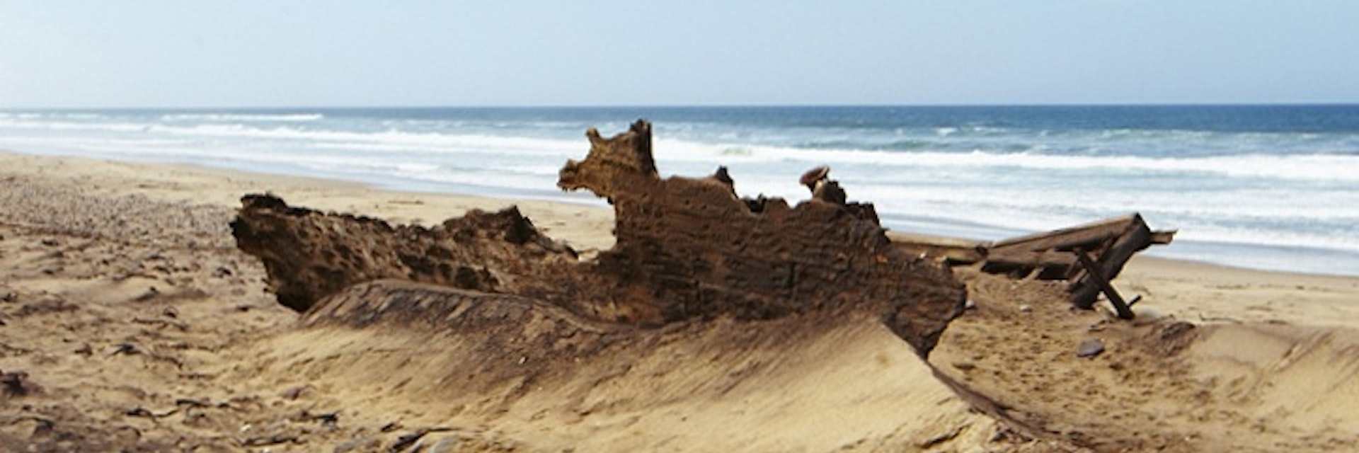 Rusting remains of Suiderkus ship wreck and whale bone on beach in Mowe Bay.