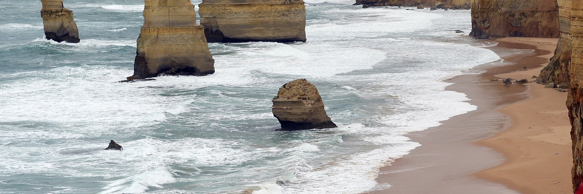 In this photo taken on March 24, 2015, waves crash into the base of natural limestone structures known as the Twelve Apostles off the shore of the Port Campbell National Park, by the Great Ocean road in Victoria. The close proximity of the collection of limestone stacks to one another has made the site a popular tourist attraction.  AFP PHOTO / INDRANIL MUKHERJEE        (Photo credit should read INDRANIL MUKHERJEE/AFP/Getty Images)
