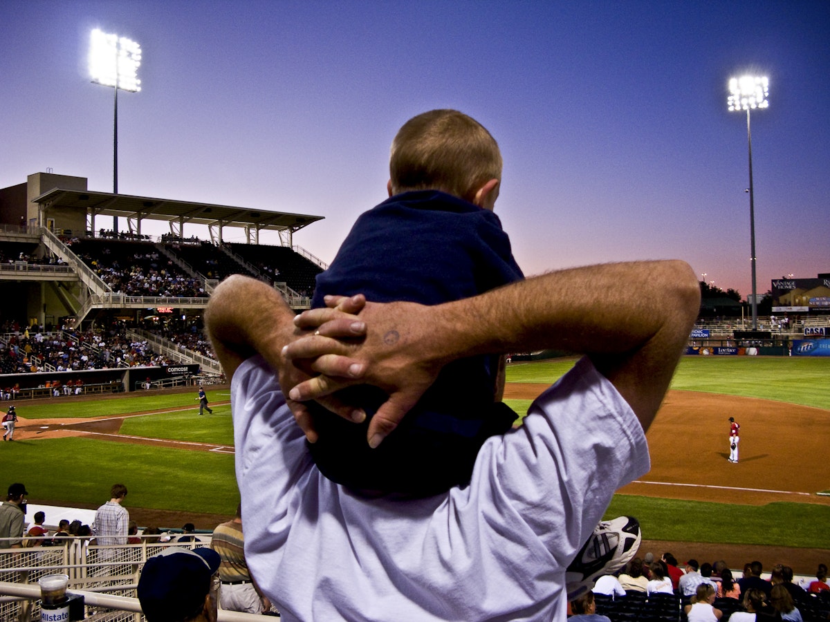 Father with son on shoulders at an Isotopes baseball game.
