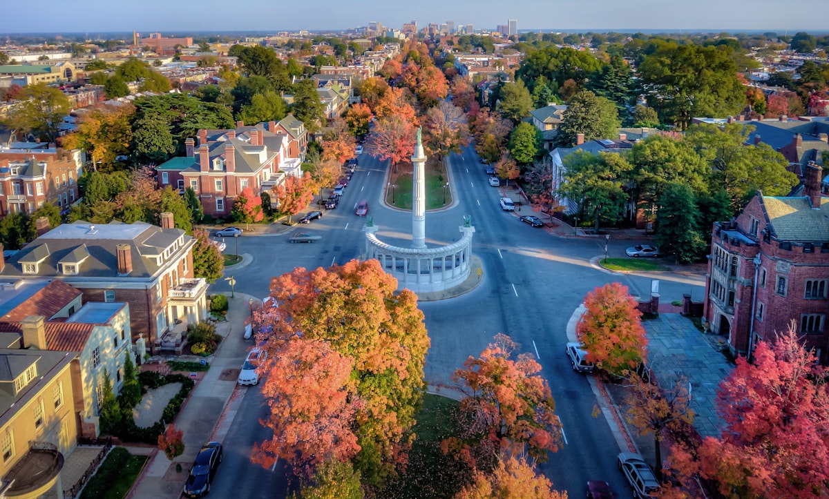 An aerial view above beautiful Fall foliage on Monument Avenue and the skyline of Richmond Virginia in the distance.