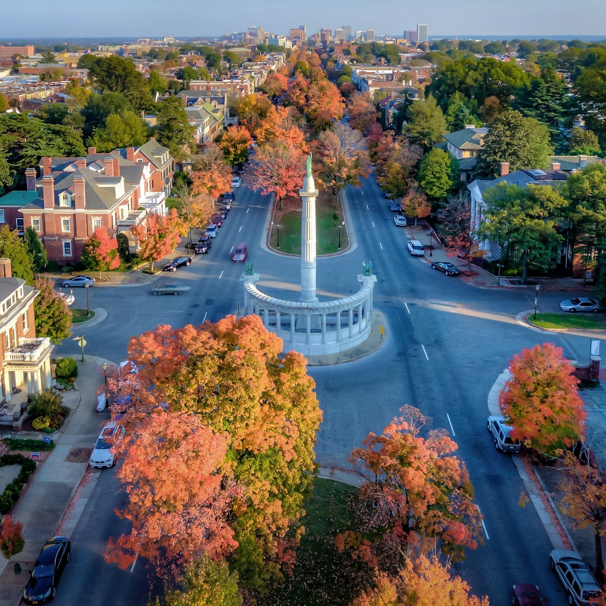 An aerial view above beautiful Fall foliage on Monument Avenue and the skyline of Richmond Virginia in the distance.