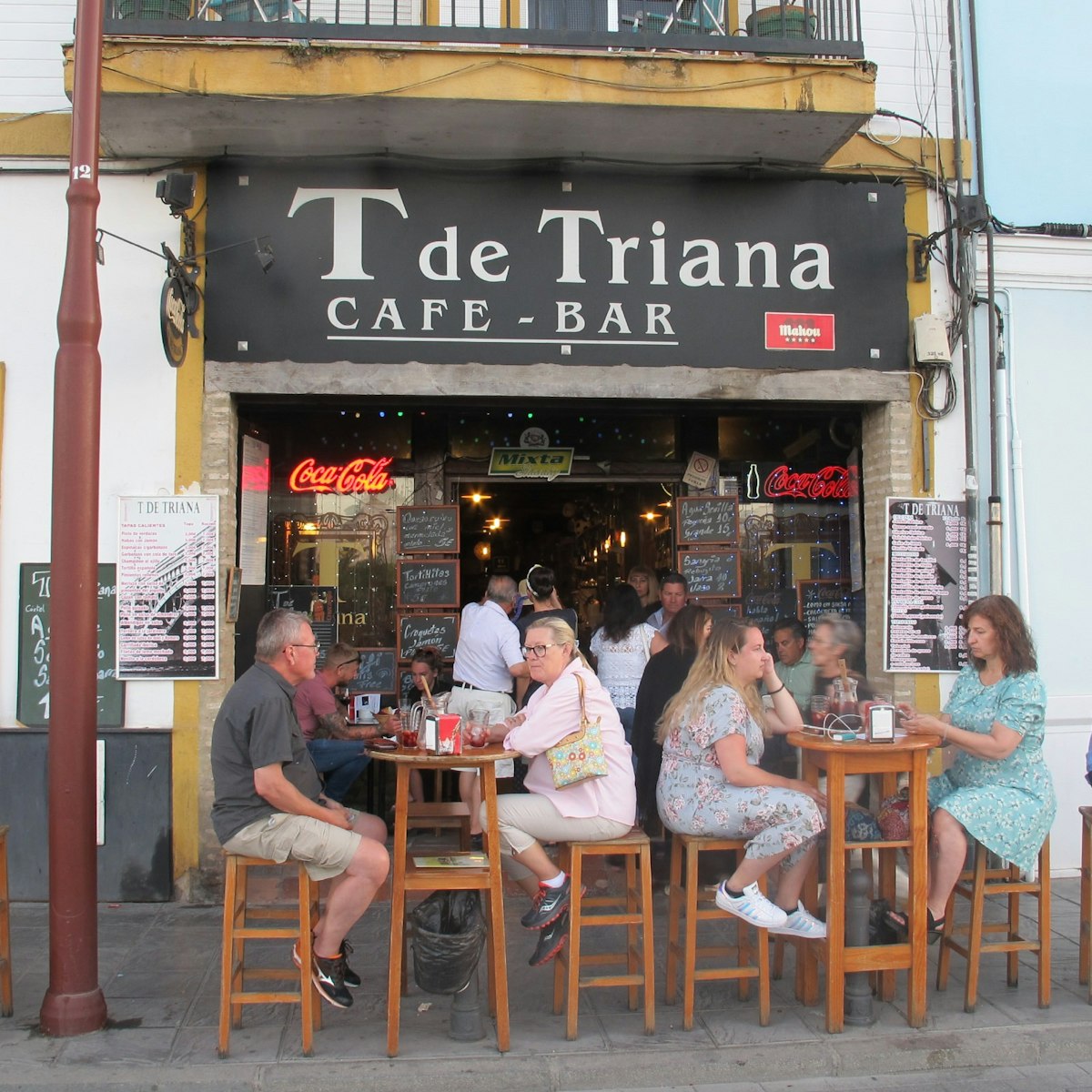 T de Triana cafe bar with people sitting on chairs outside.