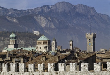 City walls in Piazza della Fiera, in the foreground, with the towers of Trento Cathedral and the Mausoleum of Cesare Battisti in the background, Trento, Trentino-Alto Adige, Italy