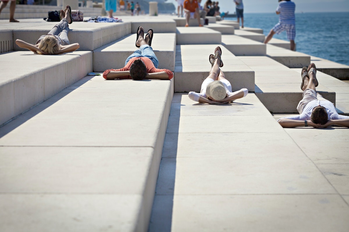 Young people sunbathing on pier, listening to Sea Organ, Zadar, Croatia