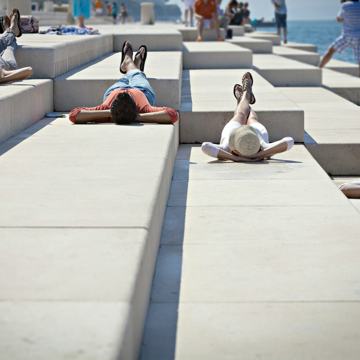 Young people sunbathing on pier, listening to Sea Organ, Zadar, Croatia