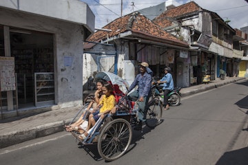 People driving in a rishka through Surabaya
