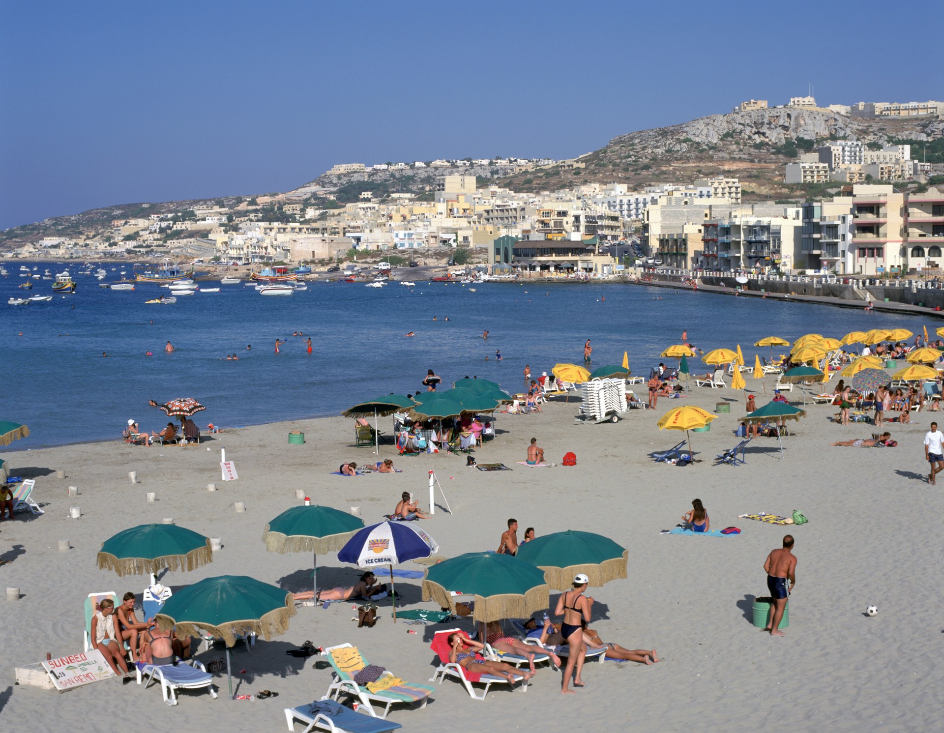Tourists gather on the beach at Mellieha Bay, Malta