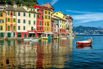 Italy, Liguria, Geneva, Portofino, Multicolored waterfront houses and harbor with anchored motor boats