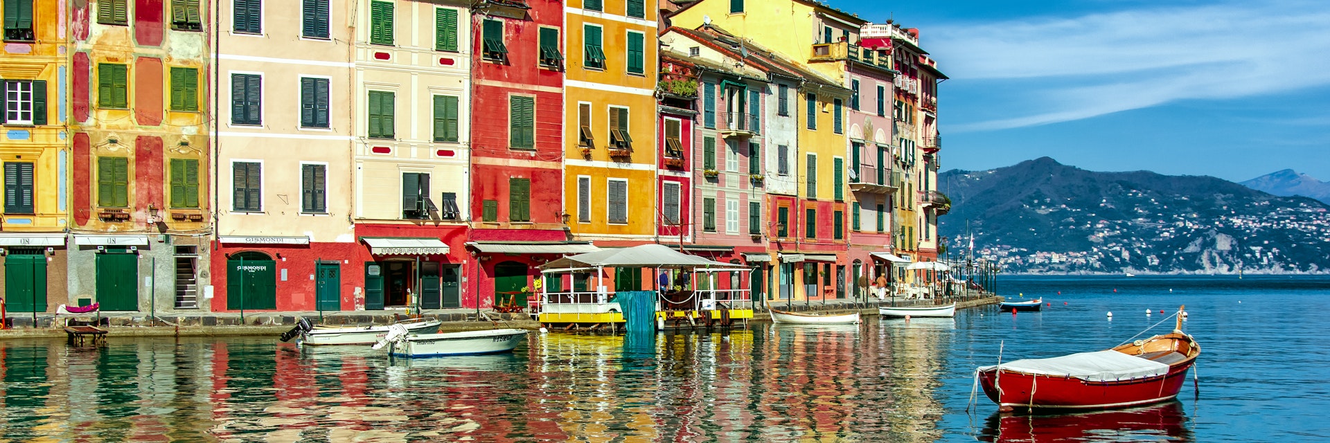 Italy, Liguria, Geneva, Portofino, Multicolored waterfront houses and harbor with anchored motor boats