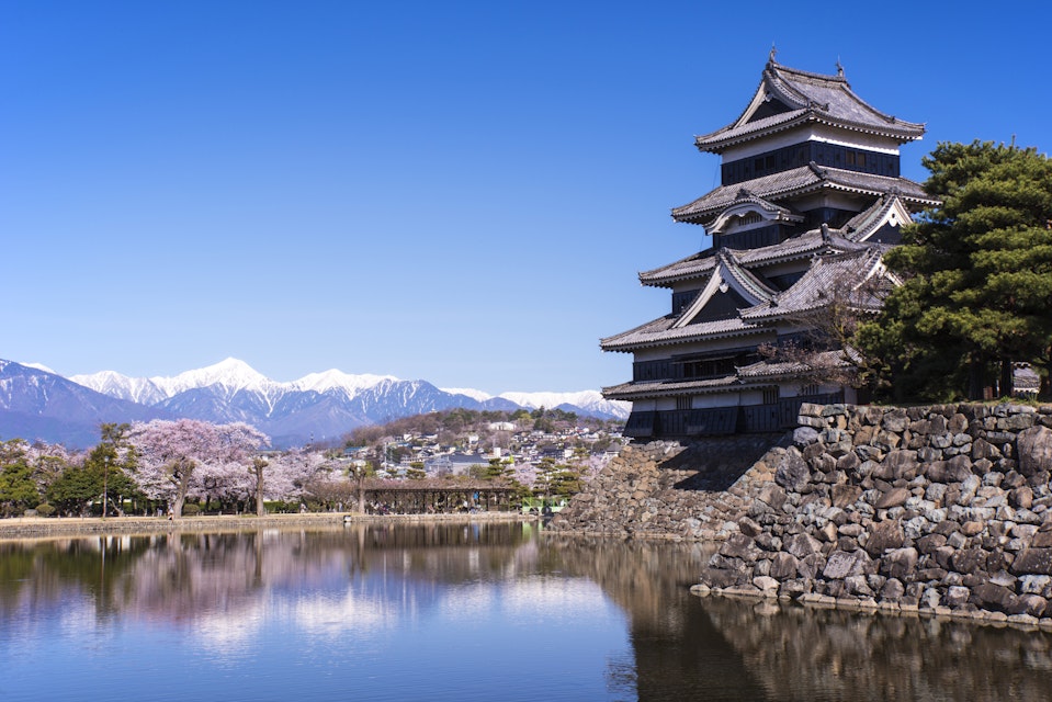 Japan, Koshinetsu Region, Nagano Prefecture, Matsumoto, View of Matsumoto Castle, Japanese Alps and cherry tree (Photo by: JTB Photo/UIG via Getty Images)