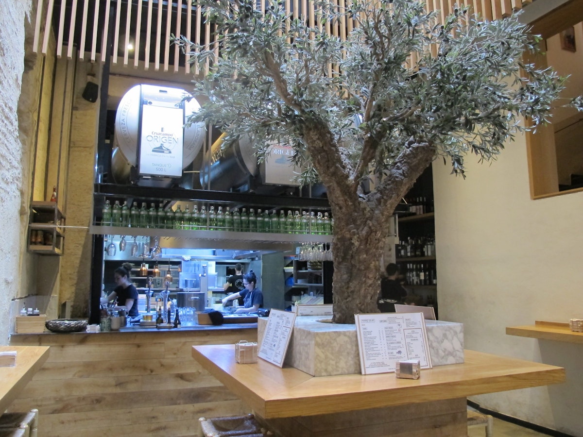 Restaurant interior - olive tree with table and open kitchen, Perro Viejo.