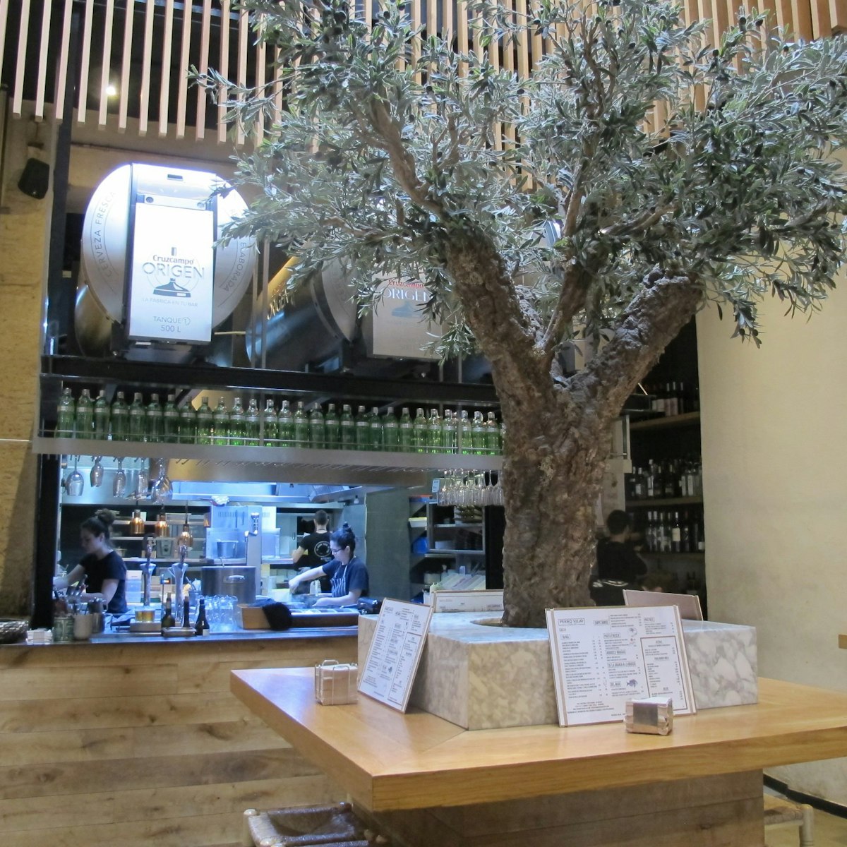 Restaurant interior - olive tree with table and open kitchen, Perro Viejo.